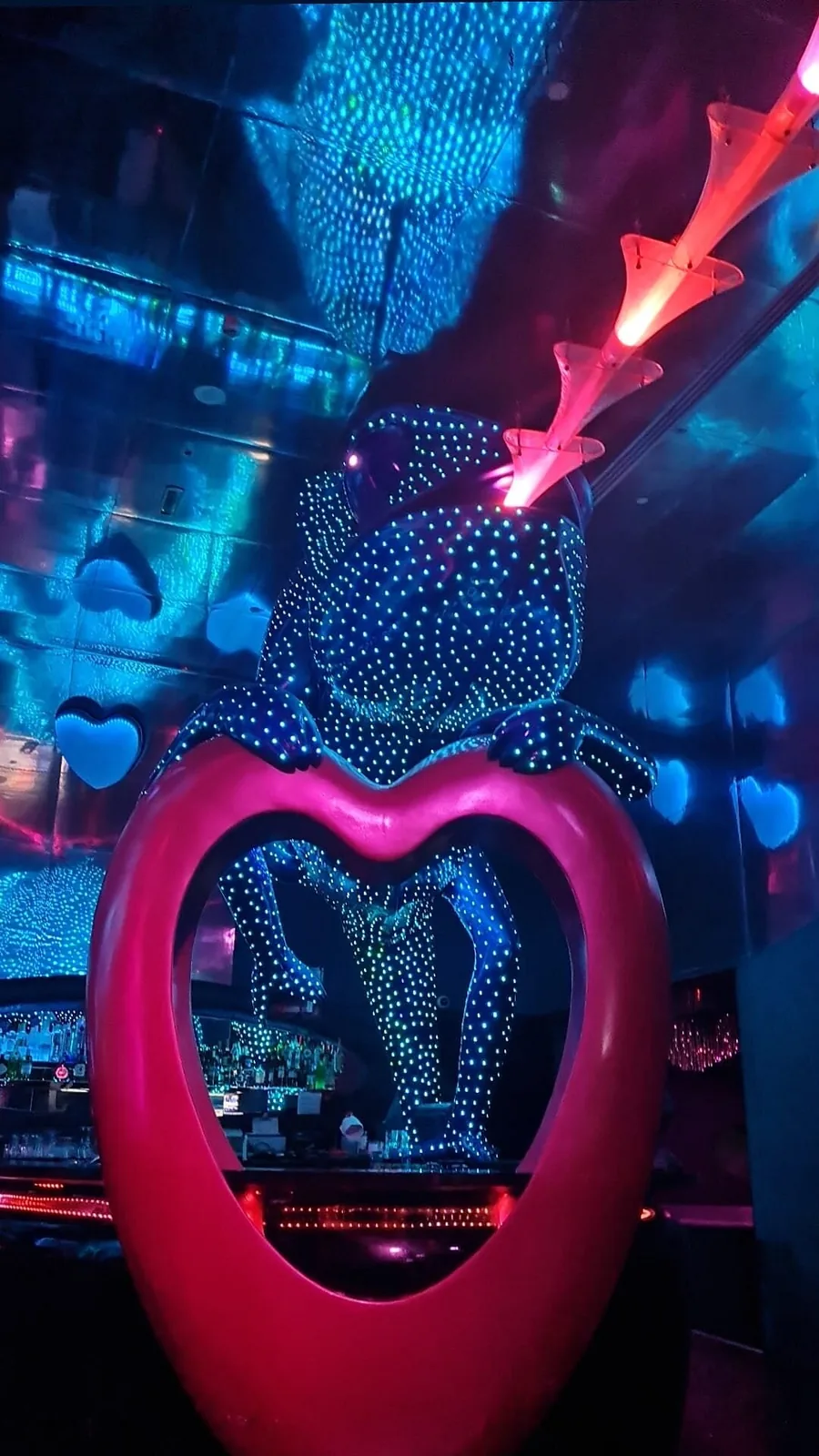 Vertical view of the pink heart sculpture under a blue LED-studded chameleon at Chameleon Club Dubai