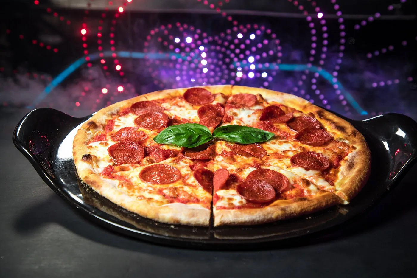 Pepperoni pizza served under neon lights