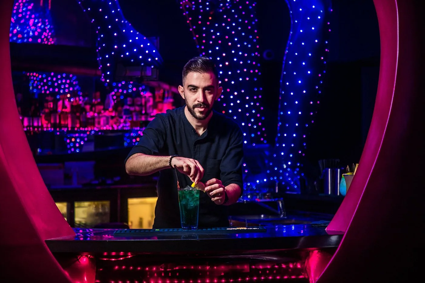 Bartender preparing drinks at the circle bar framed by the pink heart