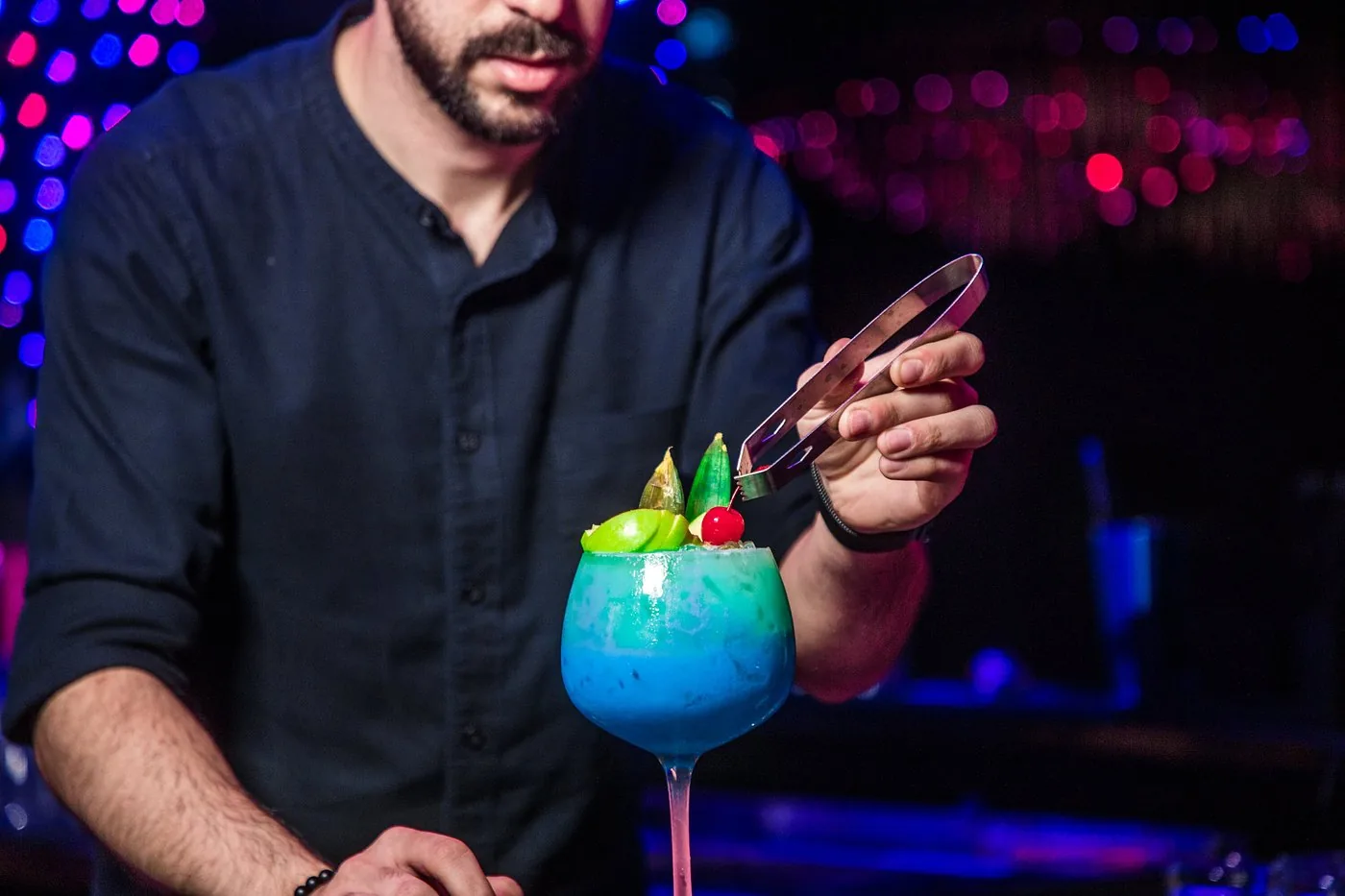 Bartender garnishing a blue signature cocktail