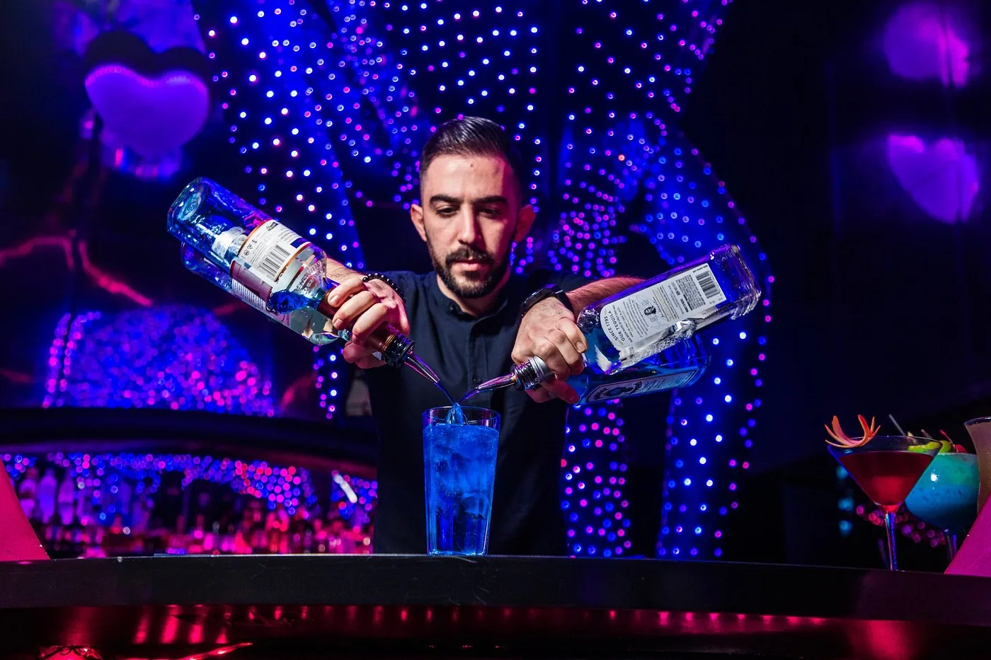 Bartender pouring a signature serve at the Chameleon Club Dubai bar